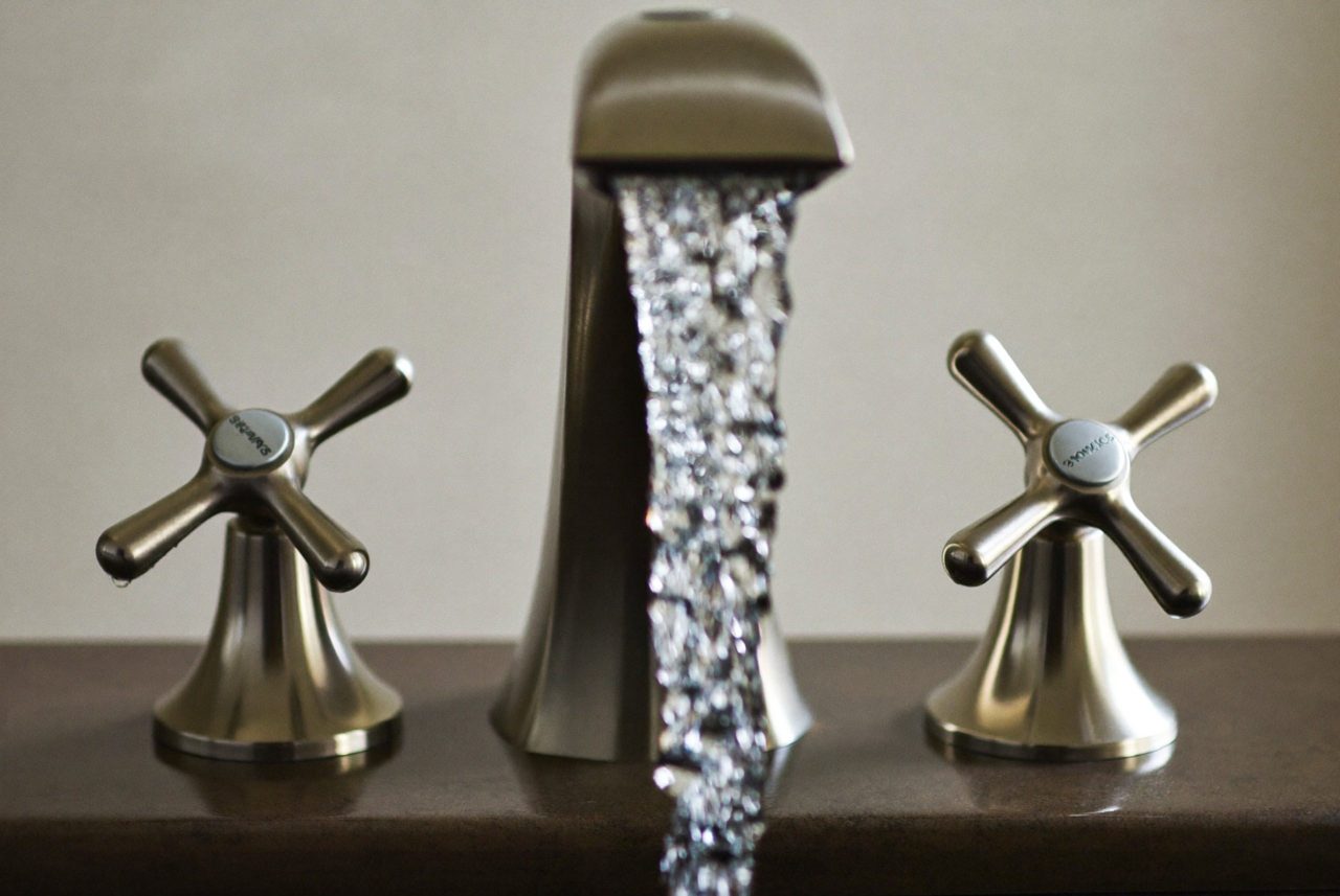 Water running from a brass tap into a basin